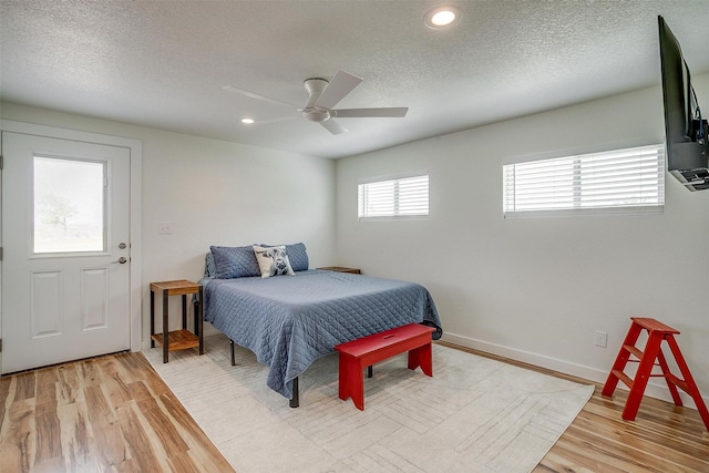 bedroom featuring light wood-type flooring, ceiling fan, and a textured ceiling