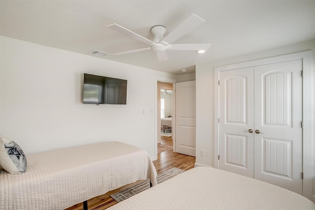 bedroom with a closet, visible vents, baseboards, wood finished floors, and a ceiling fan