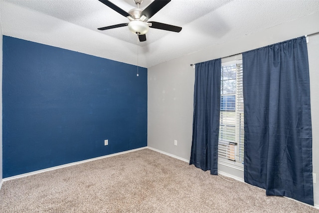 empty room featuring baseboards, carpet, a ceiling fan, and a textured ceiling