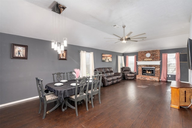 dining area with a fireplace, dark wood finished floors, a ceiling fan, lofted ceiling, and visible vents