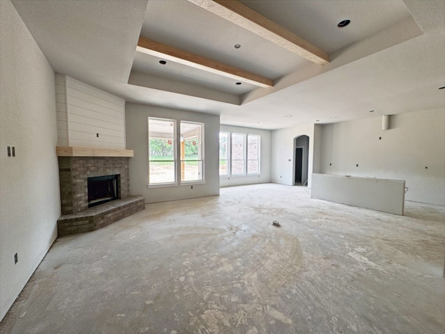 1005 Ronnie Ct, Springtown, TX 76082 - unfurnished living room featuring arched walkways, a brick fireplace, and beam ceiling