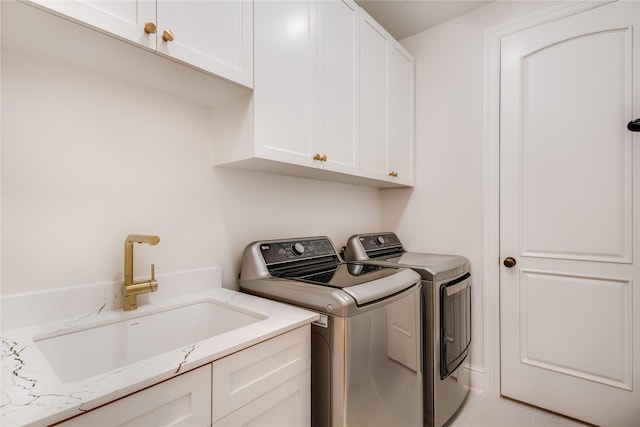 clothes washing area with a sink, cabinet space, and washer and clothes dryer