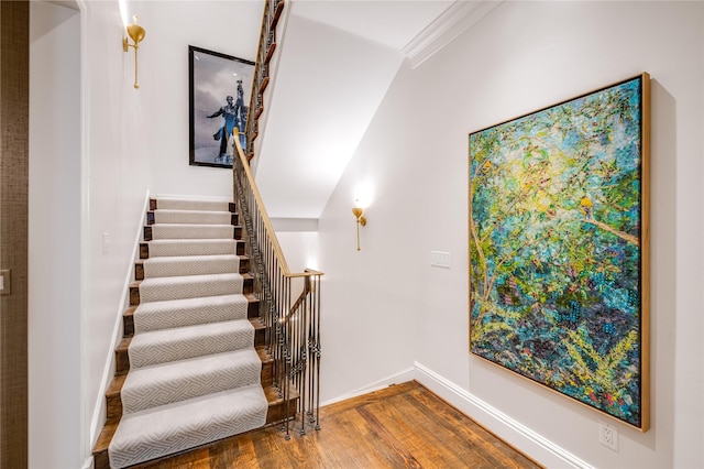 stairway featuring crown molding, baseboards, and wood finished floors