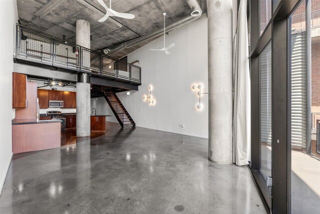 interior space featuring finished concrete flooring, a ceiling fan, and a towering ceiling
