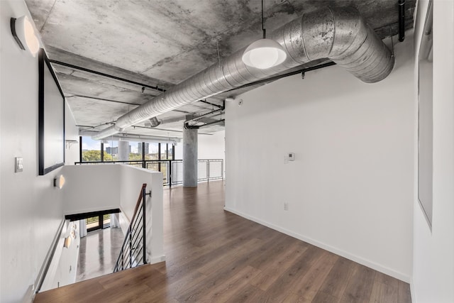 hall with baseboards, an upstairs landing, and wood finished floors