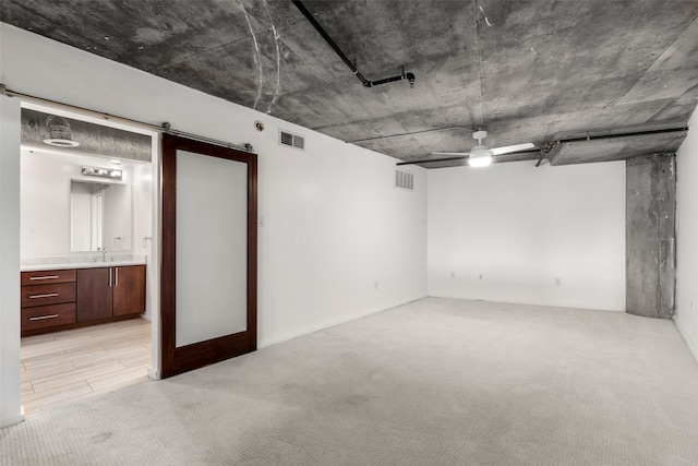 finished below grade area featuring a sink, light colored carpet, and visible vents
