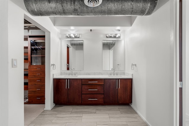bathroom featuring double vanity, baseboards, and a sink