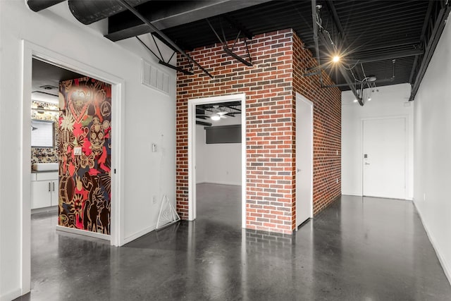 interior space with finished concrete floors, baseboards, brick wall, and visible vents