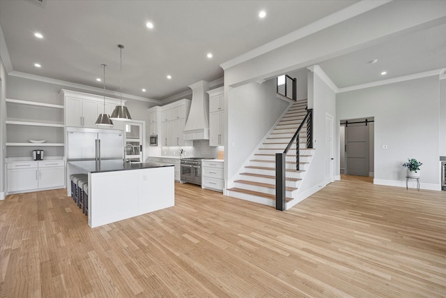909 Saint Anne Ct, Heath, TX 75032 - kitchen featuring premium appliances, a barn door, custom range hood, crown molding, and light wood-style flooring