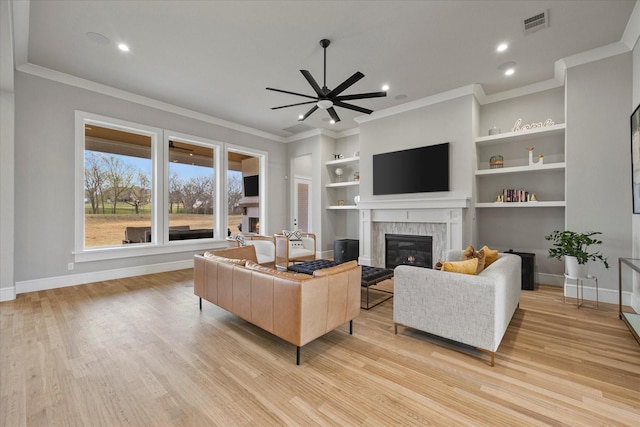 909 Saint Anne Ct, Heath, TX 75032 - living room with a glass covered fireplace, ceiling fan, baseboards, built in features, and crown molding