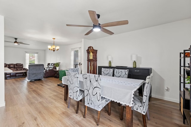 dining area with ceiling fan with notable chandelier, light wood-style floors, and baseboards