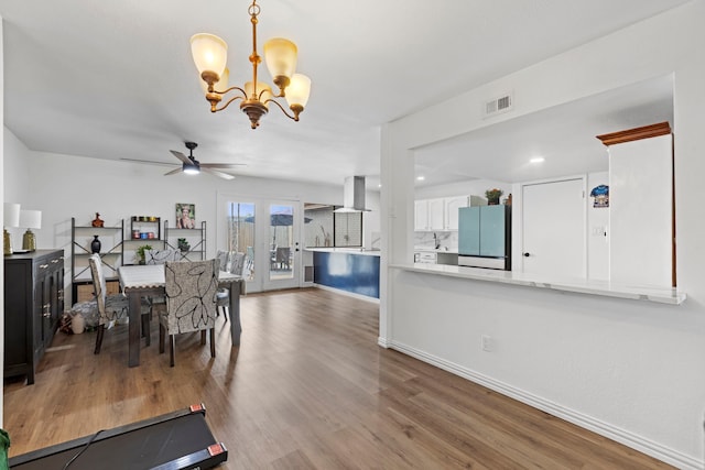 dining area with ceiling fan with notable chandelier, visible vents, wood finished floors, and baseboards