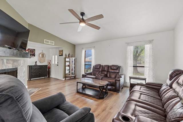 living area featuring visible vents, a fireplace, ceiling fan, lofted ceiling, and light wood-type flooring