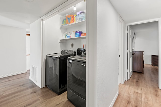 laundry area with washing machine and clothes dryer, baseboards, laundry area, and light wood-type flooring