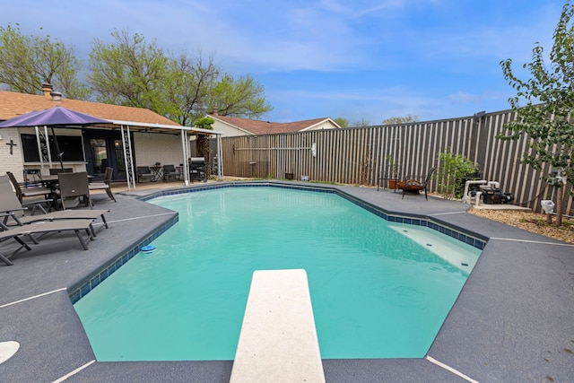 view of pool with a diving board, a fenced backyard, a fenced in pool, and a patio