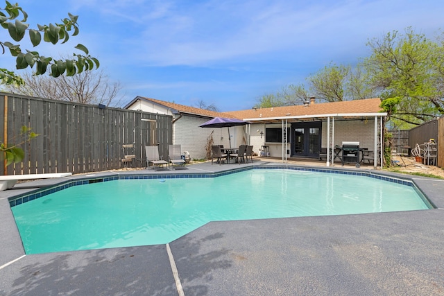 view of swimming pool featuring a patio area, french doors, a fenced in pool, a diving board, and a fenced backyard