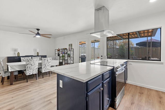 kitchen with stainless steel electric range oven, island range hood, a healthy amount of sunlight, light wood-type flooring, and blue cabinets