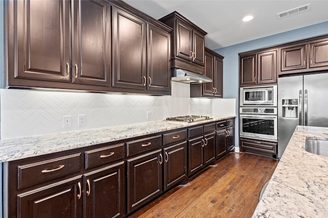 1630 Old Oak Ct, Prosper, TX 75078 - kitchen with stainless steel appliances, dark brown cabinetry, tasteful backsplash, dark wood-style flooring, and light stone countertops