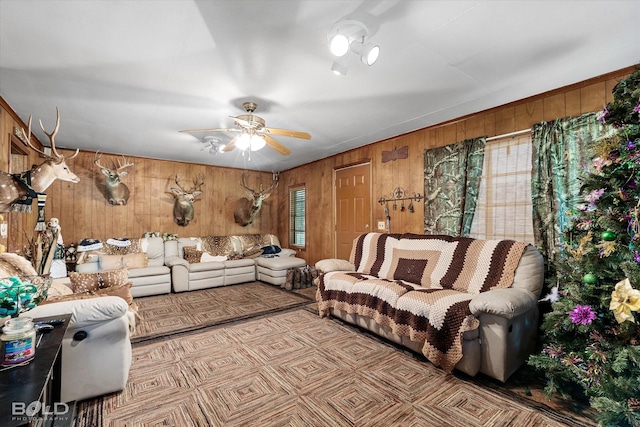 living room with a ceiling fan, plenty of natural light, and wood walls
