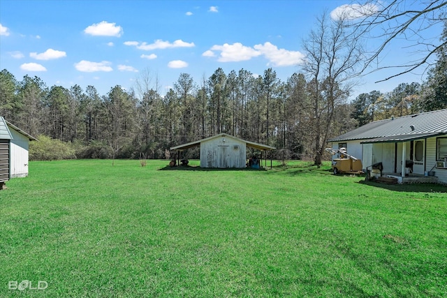 view of yard featuring a storage unit, a view of trees, and an outdoor structure