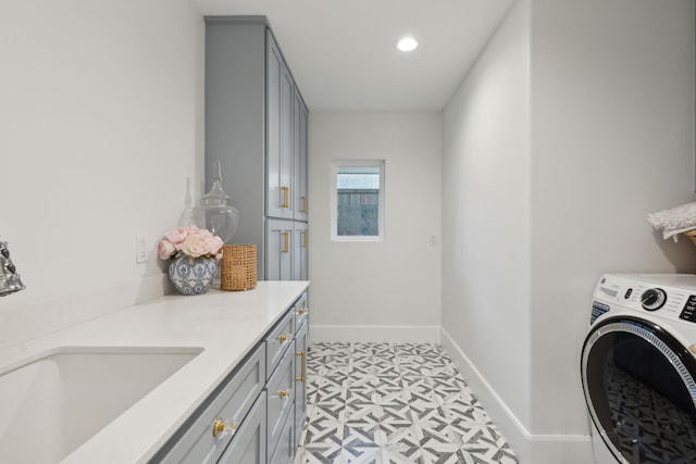 washroom featuring baseboards, washer / clothes dryer, light floors, a sink, and cabinet space