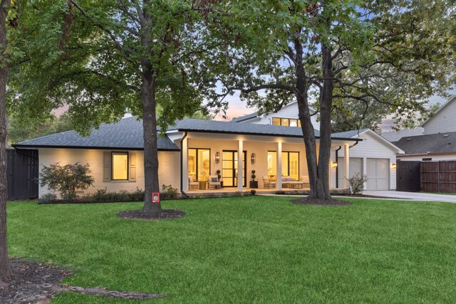 view of front of property featuring concrete driveway, fence, a garage, and a yard