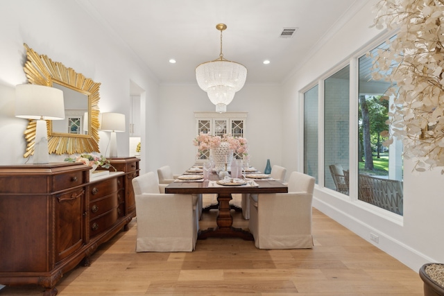 dining area with an inviting chandelier, crown molding, light wood-style floors, and visible vents