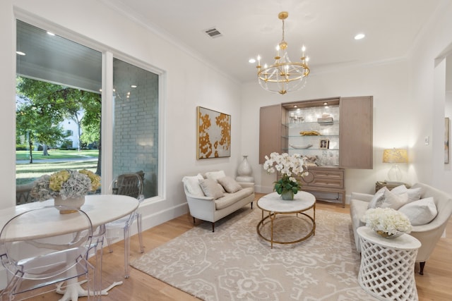 living room with visible vents, baseboards, ornamental molding, wood finished floors, and a notable chandelier