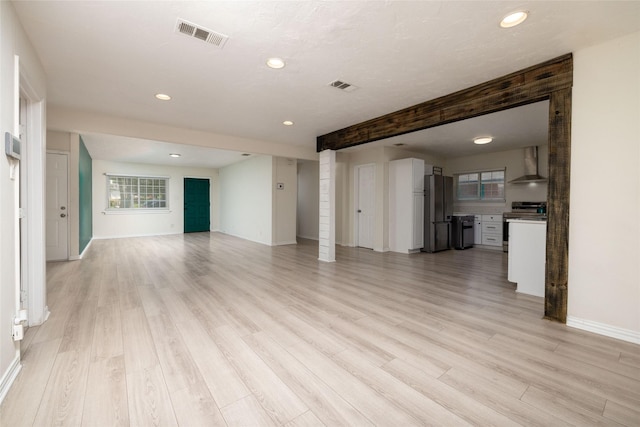 unfurnished living room with light wood finished floors, baseboards, and visible vents