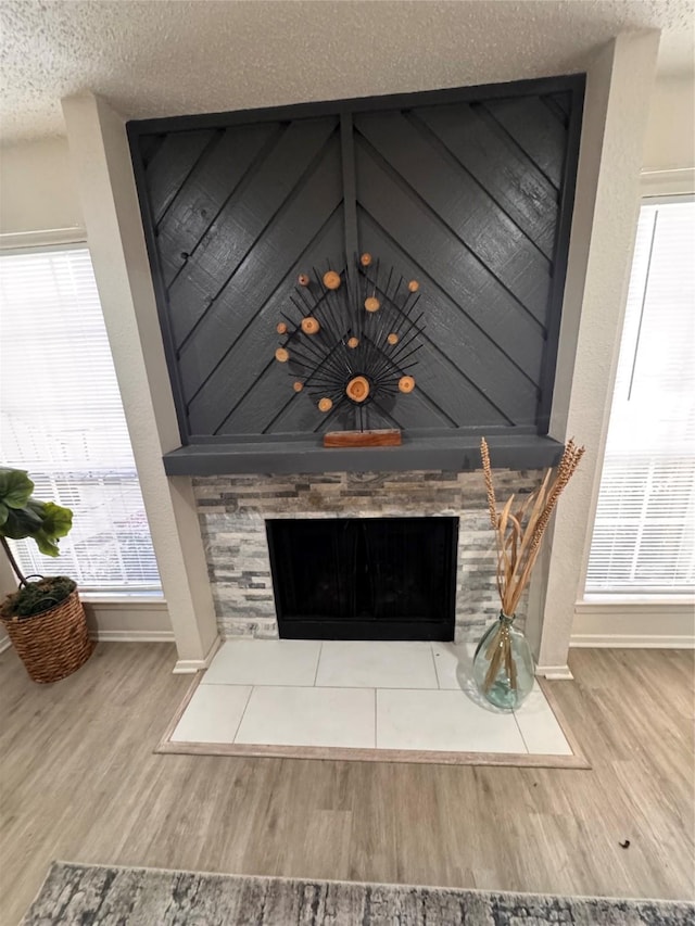 room details featuring baseboards, wood finished floors, a tile fireplace, and a textured ceiling