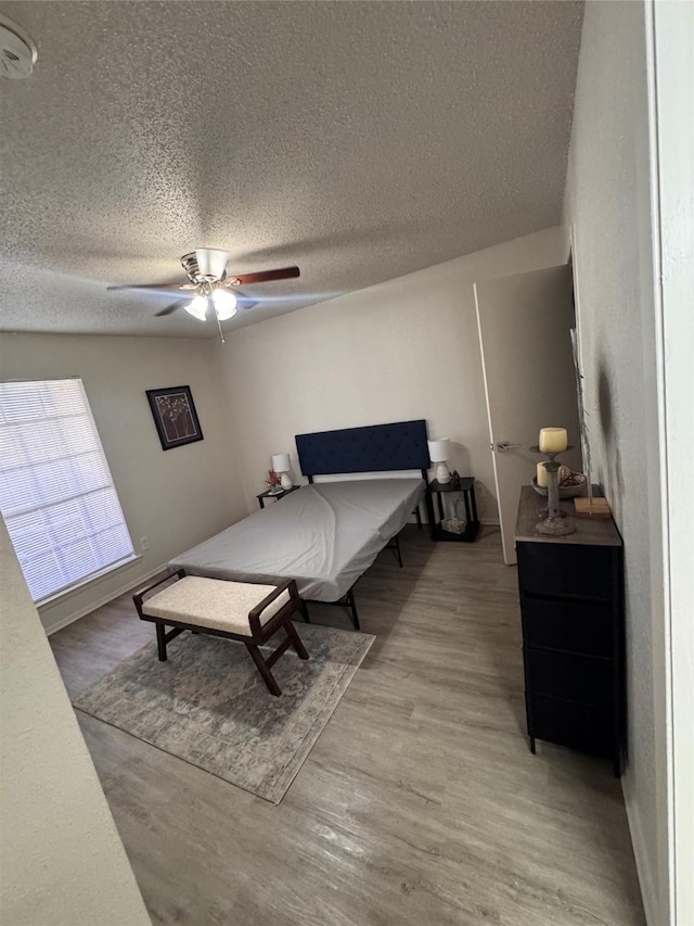 bedroom with a textured ceiling, wood finished floors, and ceiling fan