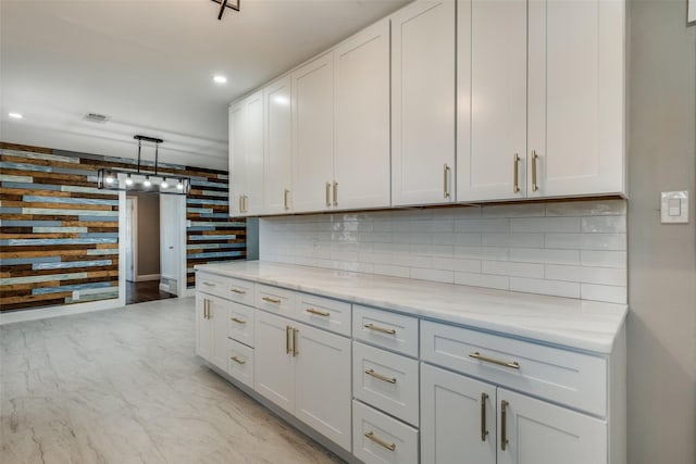 kitchen with white cabinets, visible vents, light stone counters, and tasteful backsplash