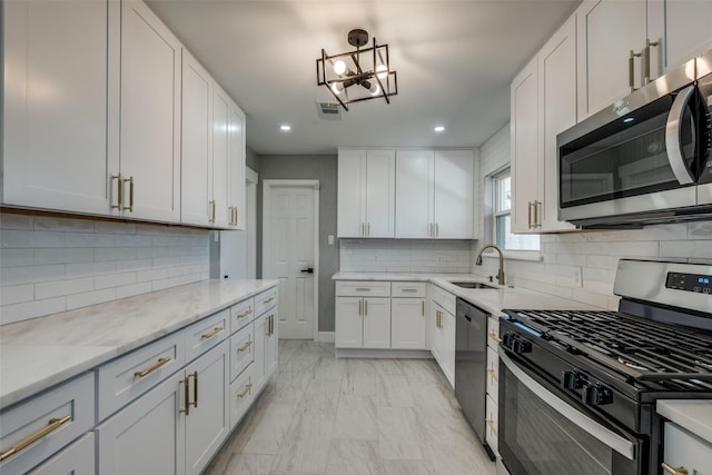 kitchen featuring visible vents, a chandelier, appliances with stainless steel finishes, white cabinetry, and a sink