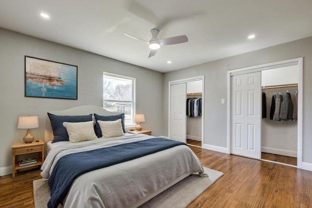 bedroom featuring baseboards, wood finished floors, and two closets