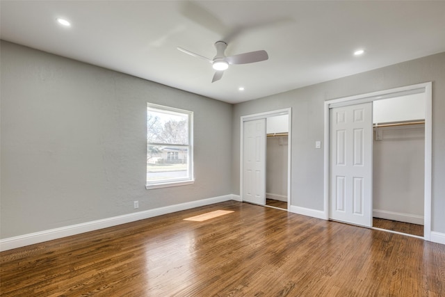 unfurnished bedroom with baseboards, multiple closets, wood finished floors, and recessed lighting
