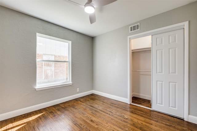 unfurnished bedroom with a closet, baseboards, visible vents, and wood finished floors