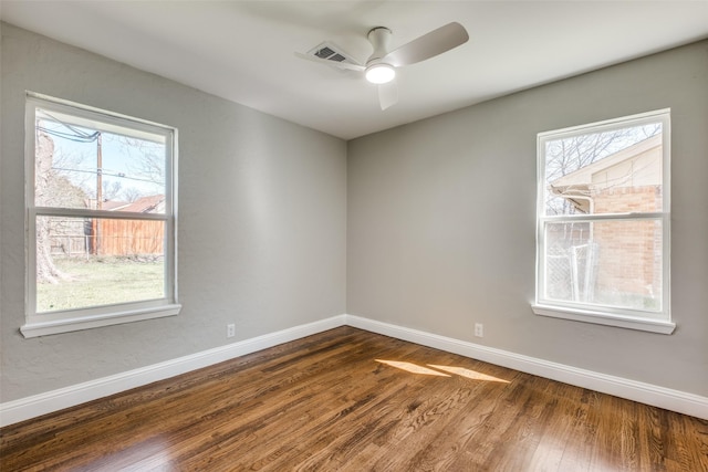 spare room with plenty of natural light, baseboards, visible vents, and wood finished floors