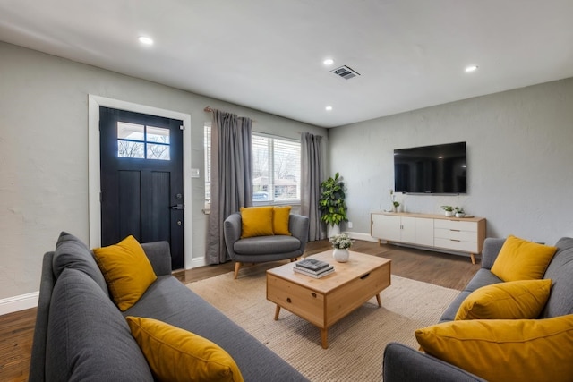 living room featuring baseboards, visible vents, wood finished floors, and recessed lighting