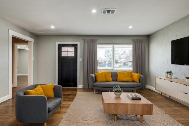 living room with visible vents, baseboards, wood finished floors, recessed lighting, and a textured wall