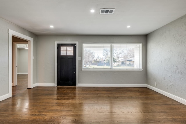 entrance foyer featuring wood finished floors, a textured wall, baseboards, and visible vents