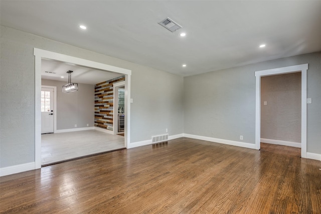 unfurnished room featuring wood finished floors, recessed lighting, baseboards, and visible vents