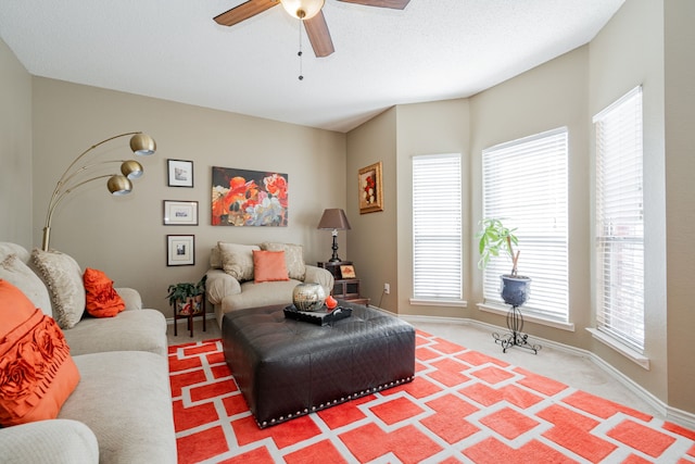 carpeted living room featuring baseboards and ceiling fan