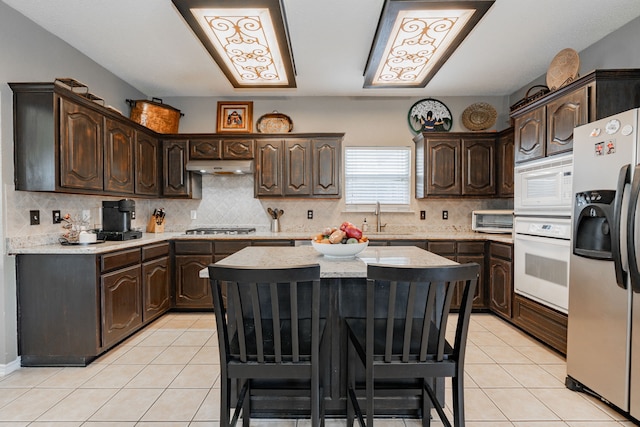 796 Ridge Rd W, Rockwall, TX 75087 - kitchen with appliances with stainless steel finishes, light tile patterned floors, dark brown cabinets, a kitchen island, and a sink