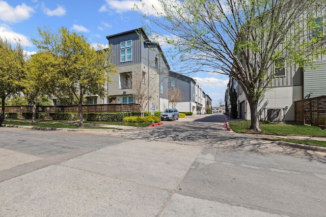 view of asphalt road featuring curbs, sidewalks, and a residential view