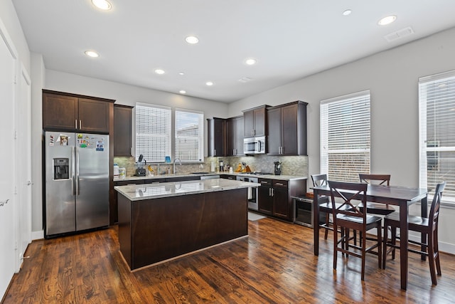 kitchen with stainless steel appliances, dark brown cabinetry, a center island, decorative backsplash, and recessed lighting