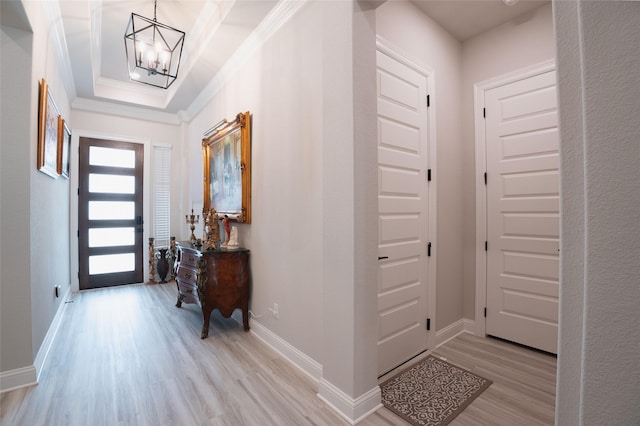 entrance foyer with crown molding, baseboards, an inviting chandelier, and light wood-style floors