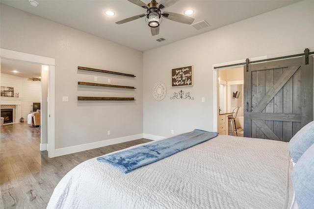 bedroom featuring baseboards, wood finished floors, visible vents, and a barn door