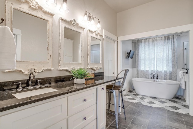 bathroom with tile patterned flooring, a freestanding bath, and vanity