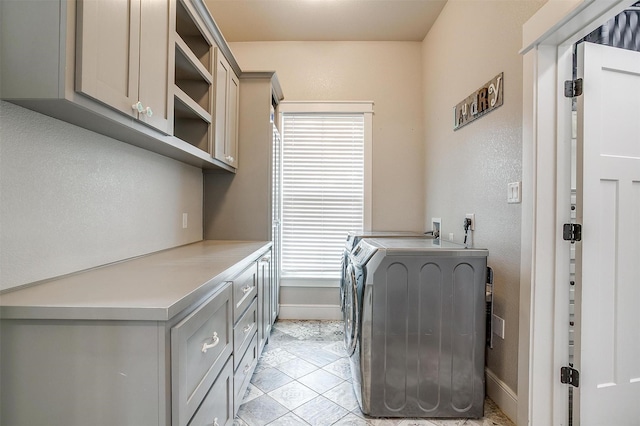 laundry area featuring cabinet space, baseboards, washer and dryer, and light tile patterned floors