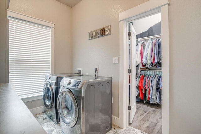 clothes washing area featuring baseboards, separate washer and dryer, and laundry area
